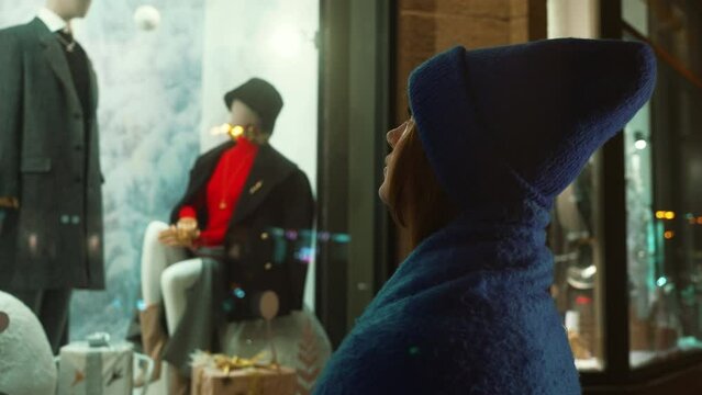 Woman in blue knit hat and fur collar gazes longingly at mannequin, her wistful expression reflecting yearning for unattainable winter fashion. Latest winter fashion trends. Essence of seasonal style