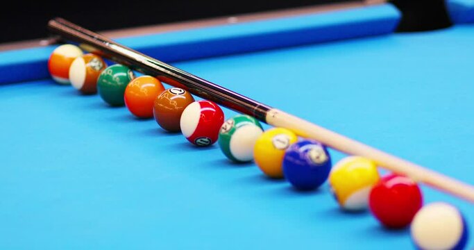 Hands of man aligns balls during pool game training on blue table