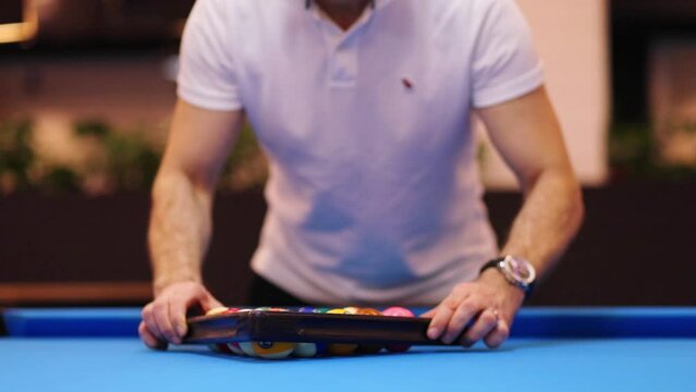 Male hands align balls with triangle during pool game, slow motion, noface