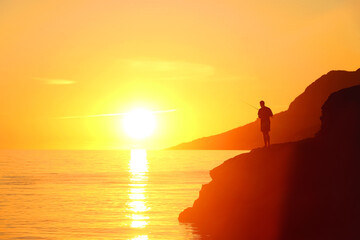 Unrecognizable person fishing on the beach at sunset. Beautiful landscape in Brela, Croatia.