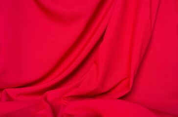 Stylish red fabric with folds and empty space for text in top left corner. Beautiful background for advertising or design. Flat lay, close-up, top view, copy space, mock up, blank