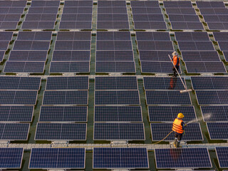 Worker Cleaning  floating solar panels or solar cell Platform system on the lake with brush and water. Worker cleaning solar modules in a Solar Energy Power Plant