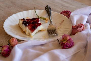 Cold cheesecake with cherry jelly served on wooden table with forks flowers roses and green veil