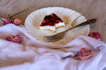 Cold cheesecake with cherry jelly served on wooden table with forks flowers roses and green veil