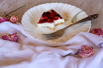 Cold cheesecake with cherry jelly served on wooden table with forks flowers roses and green veil
