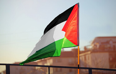 Palestinian flag waving against the light in the city suburb