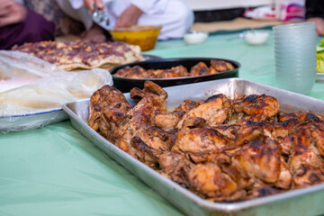 grilled Chicken tray ready to be eaten with people hands and musakhan bread