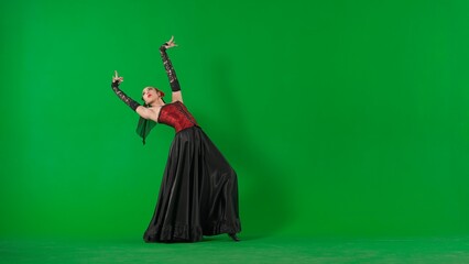 Fototapeta premium Woman dancer dancing on chroma key green screen. Female in flamenco style dress performs elegant spanish dance moves with her hands and body in the studio.