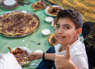 Portrait Of boy making vector gesture or two number with hand while eating with family and smile