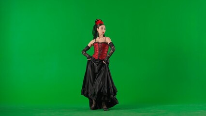 Fototapeta na wymiar Woman dancer dancing on chroma key green screen. Female in flamenco style dress performs elegant spanish dance moves with her hands and body in the studio.