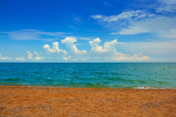 sandy sea beach at summer day, emerald sea with cloudy sky seasonal scene