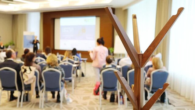 Speaker and audience during conference, focus on wooden hanger