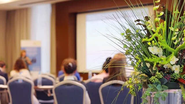Speaker and audience during conference, focus on green plant