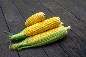 Close up view of raw corn cobs on wooden surface
