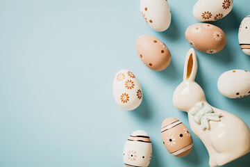 Happy Easter concept. Beautiful floral painted Easter eggs and ceramic bunny on pastel blue background.