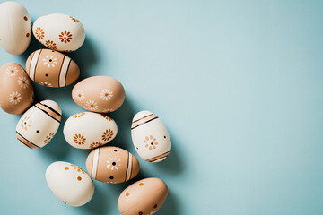Floral painted eggs in natural colors on pastel blue background. Happy Easter concept.