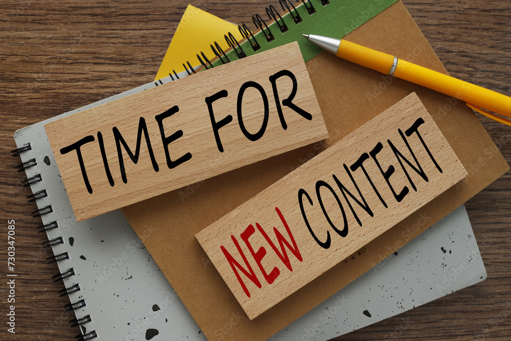 Poster time for new content, text on wooden blocks on a notepad