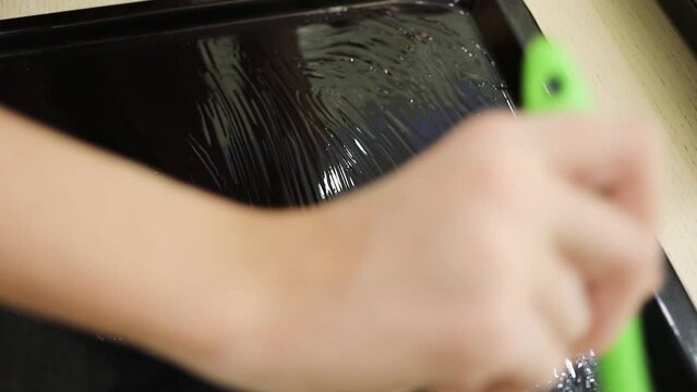 Child hand oil baking sheet for baking at home on table