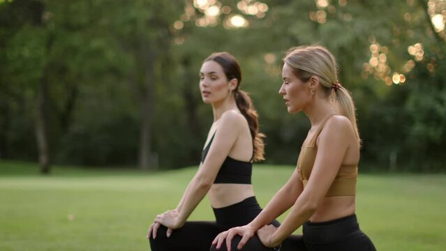Two pretty young woman doing stretching in the park