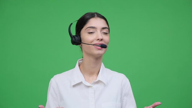 Portrait of a happy young Caucasian woman helpdesk worker talking using headset on green background. Telemarketing, remote customer support.
