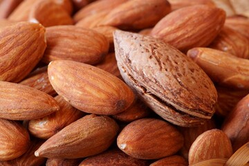 Beautiful background with raw almonds in brown shell; closeup photography
