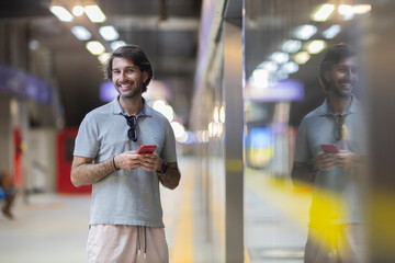 View of young man using a smartphone inside a subway - metro station with a blurred view landscape...