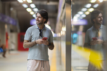 View of young man using a smartphone inside a subway - metro station with a blurred view landscape...