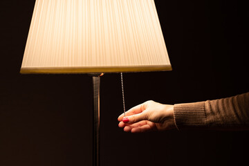 woman's hand turns on the floor lamp