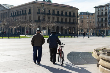 Older gentlemen strolling with bicycles in hand. Castle Square, Pamplona