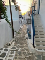 Typical street of greek traditional village with white walls and colorful doors, windows and balconies Sunset on Mykonos Island, Greece, Europe