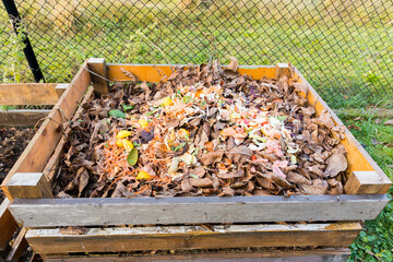 A composter made of wooden boards filled with bio-waste from the kitchen.