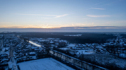 As dawn breaks, this aerial image captures a small town wrapped in the embrace of winter. The...