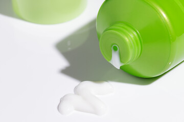 Green plastic cosmetic tube with beauty cream on white background. Mockup