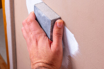 Painter sanding a surface after plaxte is applied