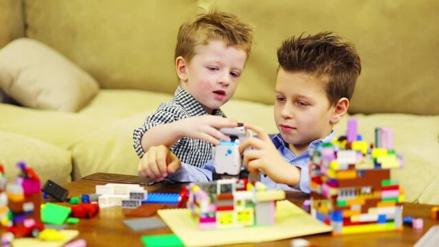Two happy boys play with robot and with tinker toys, slow motion