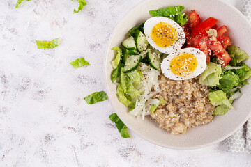 Breakfast oatmeal porridge with boiled eggs, tomato, cucumber and onions. Healthy balanced food. Trendy food. Top view, flat lay