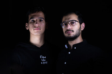 Teenager and young man of different nationalities smiling together in the studio in light and darkness