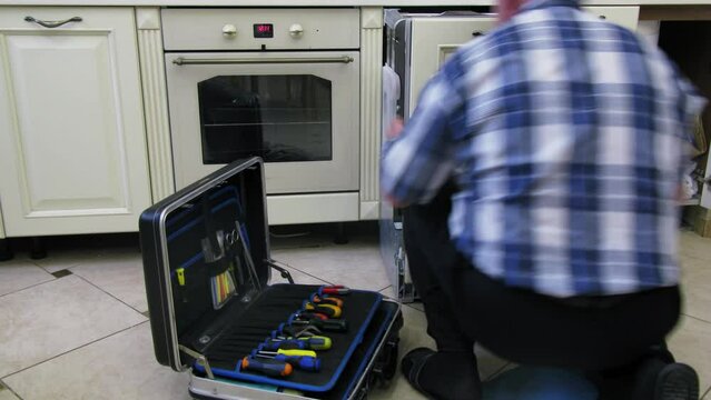  Worker installs dishwasher into kitchen furniture. Timelapse