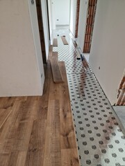 A photo of a wooden floor being installed in a hallway. The photo shows a wooden floor being installed in a hallway. The floor is made of light brown wood and has a smooth finish. The walls in the hal