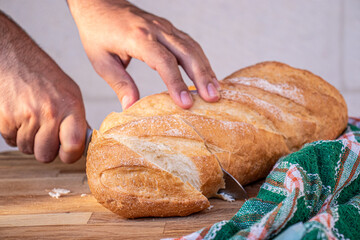 hands holding the knife and cutting the bread into slices to be served