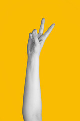 Abstract hand gesture of victory or v sign. Black and white woman hand isolated on yellow background