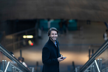 Obraz premium View of young man using a smartphone at twilight in an indoor space