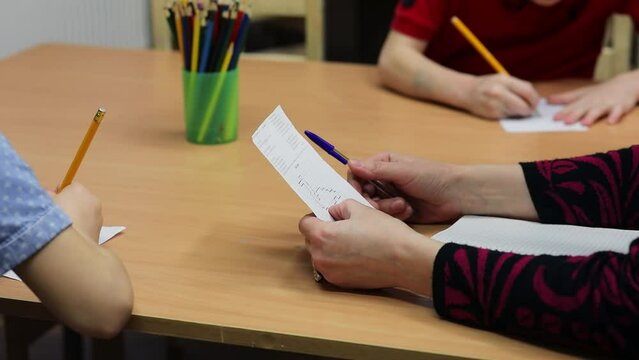 Educator checks paper with picture and children draw near