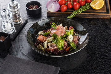 Salad with Parma and Gorgonzola on a black stone tray