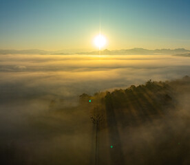Aerial view amazing the sea of mist at beautiful sunrise...slow floating fog blowing cover on the top of mountain look like as a sea of mist. ..white cloud in blue sky over the perfect forest. © Narong Niemhom
