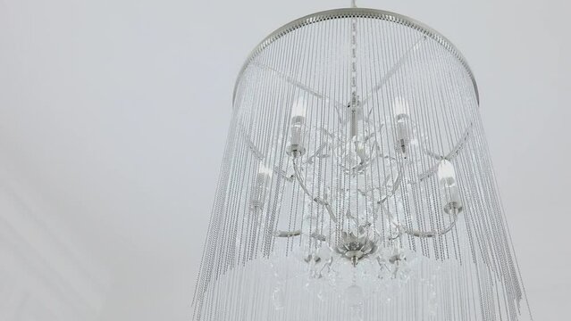 Lustre with beads hangs on white ceiling in photo studio