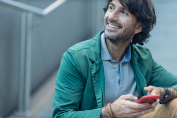 View of young man using a smartphone at indoor space with a blurred view landscape
