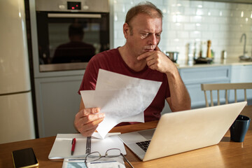 Stressed man going over bills at home