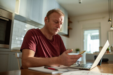 Stressed man going over bills at home