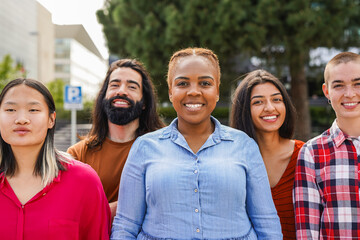 Young multiracial people having fun together in the city - Diverse millennial friends smiling in front of camera outdoor